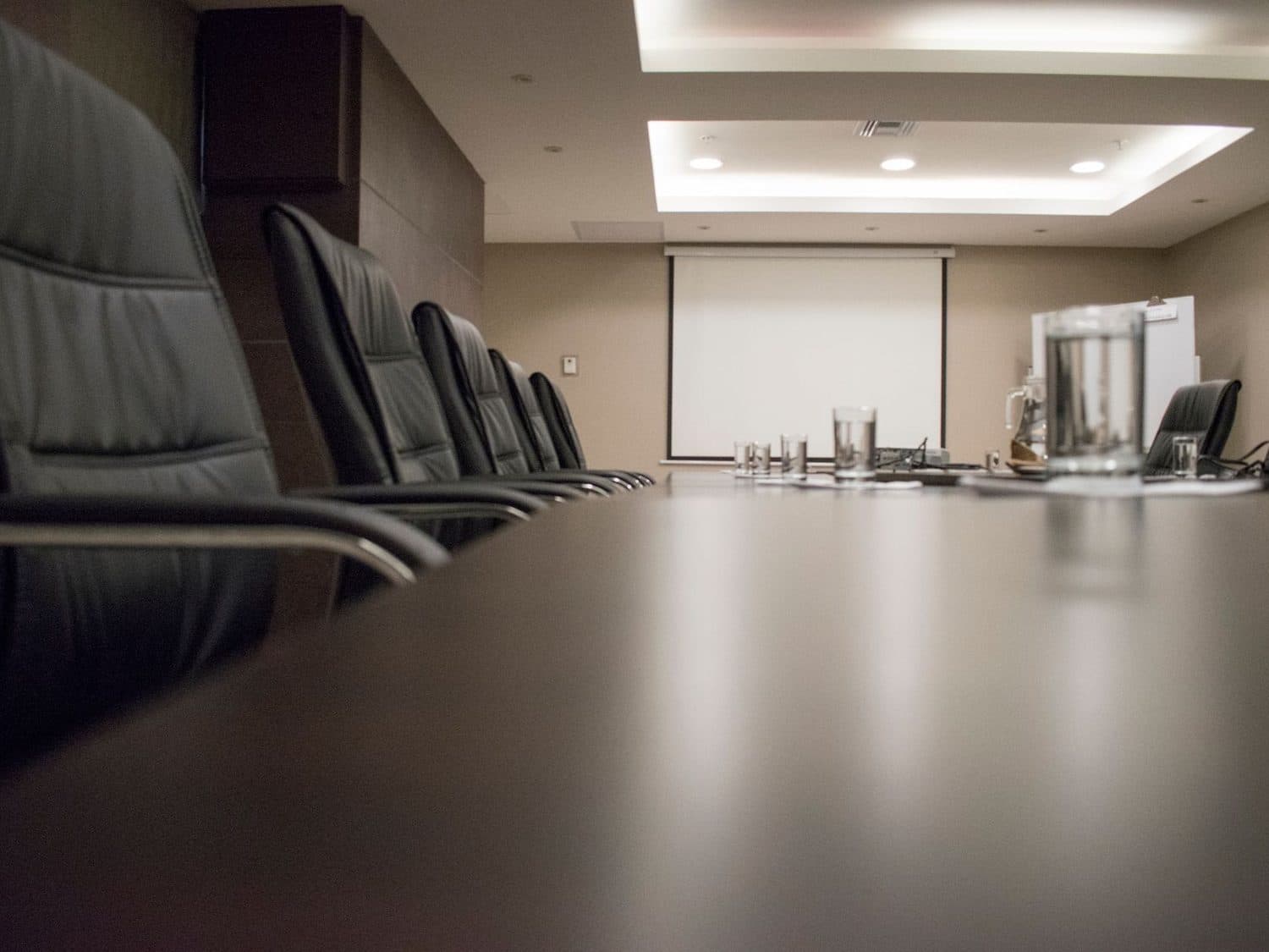 An empty boardroom, chairs drawn up along a long table